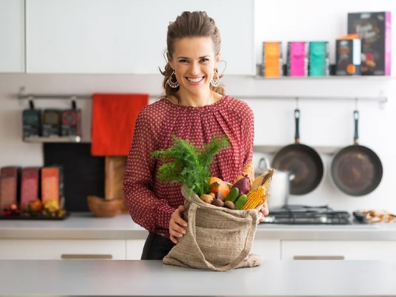 Woman smiling with groceries in kitchen