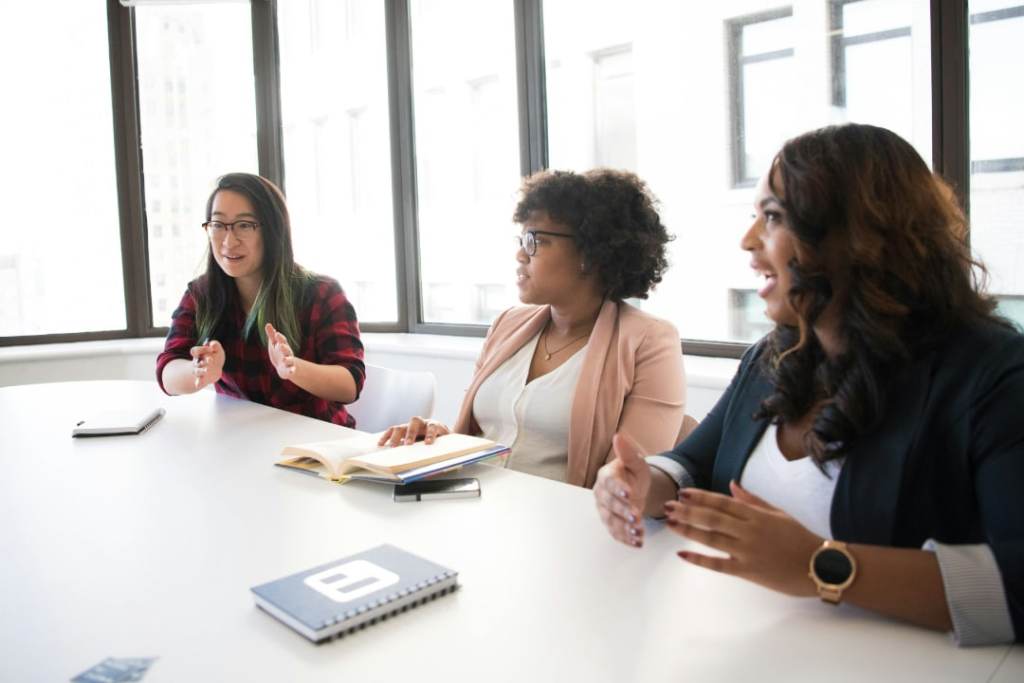 women employees smiling and discussing topic in office